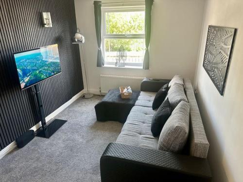 a living room with a couch and a flat screen tv at Your Stylish Totterdown Haven in Bristol