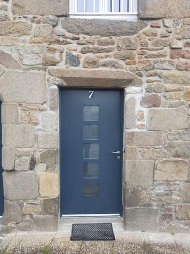 eine blaue Tür in einem Steingebäude mit einem Fenster in der Unterkunft Cosy appartement in Miniac-Morvan