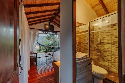 a bathroom with a toilet and a glass shower at Hotel Pietrasanta in Guatapé