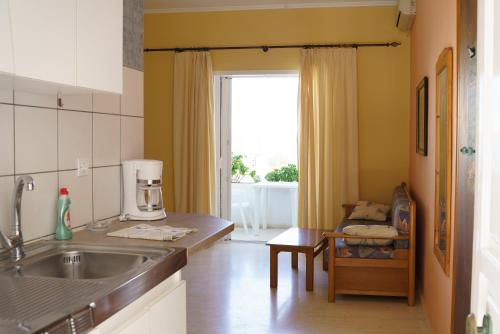 cocina con fregadero, mesa y ventana en Sigma Hotel, en Paralia Vrachou