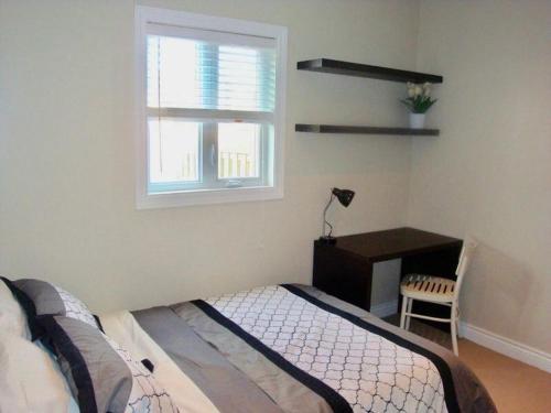 een slaapkamer met een bed, een bureau en een raam bij Comfortable apartment in Kingston