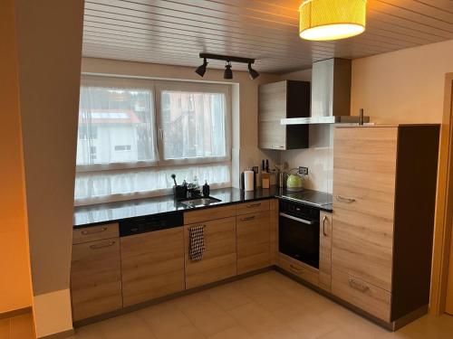 une cuisine avec des placards en bois et une grande fenêtre dans l'établissement Appartement de vacances "La Poste", à Saignelégier