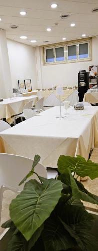 a room with white tables and chairs and plants at Hotel Palace Masoanri's in Reggio Calabria