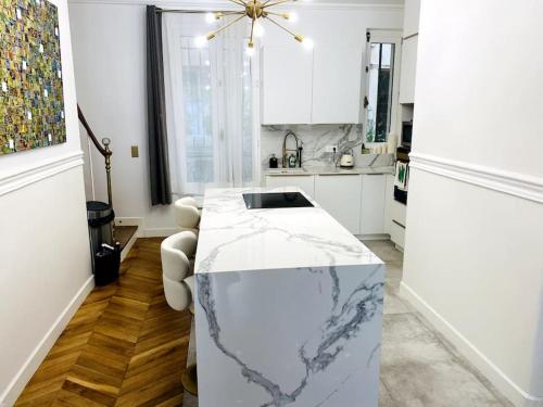 - une cuisine blanche avec un comptoir en marbre au milieu dans l'établissement Triplex à Montmartre - Sauna, à Paris