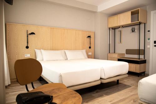 Un dormitorio con una gran cama blanca y una mesa en Hotel Dos Rios Origen en Aínsa