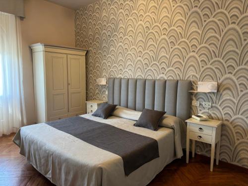 a bedroom with a large bed and a wall at Hotel Bellevue in Gardone Riviera