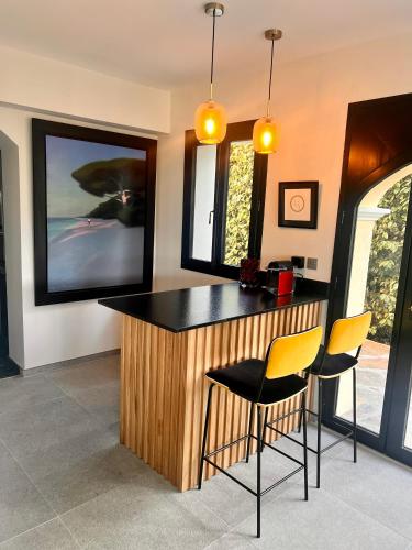 a kitchen with a bar with two chairs and a tv at Villa familiale avec vue imprenable in Saint-Raphaël