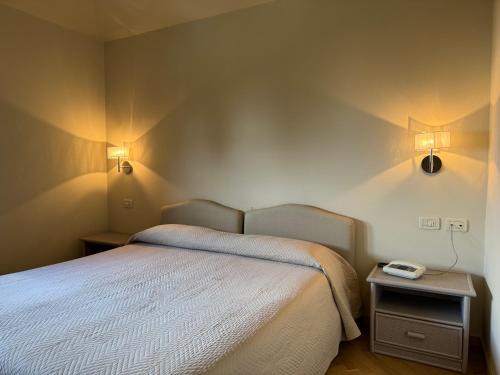 a bedroom with a bed and two lights on the wall at Hotel Bellevue in Gardone Riviera