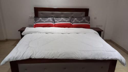 a bed with red and white pillows on it at Apartment A2R Danny in Ogbojo
