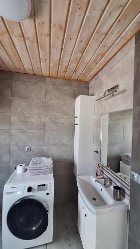 a bathroom with a washing machine and a sink at Domki Komfort całoroczne in Zator
