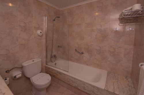 a bathroom with a shower and a toilet and a tub at Hotel Sablón in Llanes