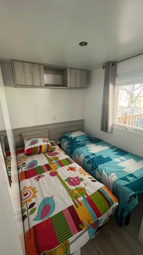 une chambre avec deux lits et une fenêtre dans l'établissement Sbvacances Mobil Home 3ch 2sdb sur Magnifique emplacement avec vue sur la forêt des landes, à Saint-Julien-en-Born
