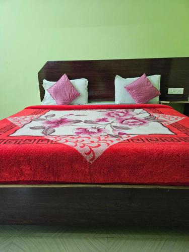 a large bed with a red blanket and pillows at Pavithra cottage munnar in Munnar