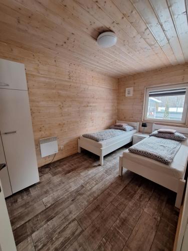 two beds in a room with wooden walls at Domki Komfort całoroczne in Zator