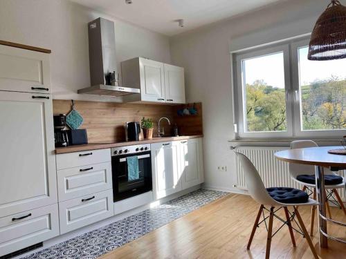 a kitchen with white cabinets and a table with chairs at Ferienwohnung Lieblingsplatz in Tholey