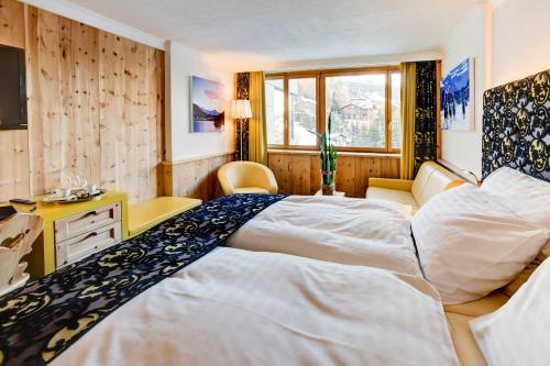 a bedroom with a large bed and a desk at Sport & Wellnesshotel San Gian St. Moritz in St. Moritz