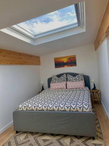 Cet appartement comprend une chambre dotée d'un lit et d'une lucarne. dans l'établissement Duplex Argenté T3 à 20 min de Paris Saint Lazare, à Argenteuil