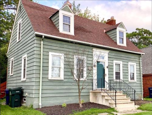 a green house with a brown roof at Cute 2 Bedroom Home - Huge backyard, near downtown! in Cleveland