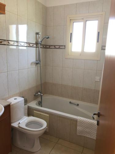 a bathroom with a toilet and a tub and a window at Budget Escape to the seaside in Larnaca