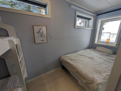 a small bedroom with a bed and two windows at Romslig leilighet in Tromsø
