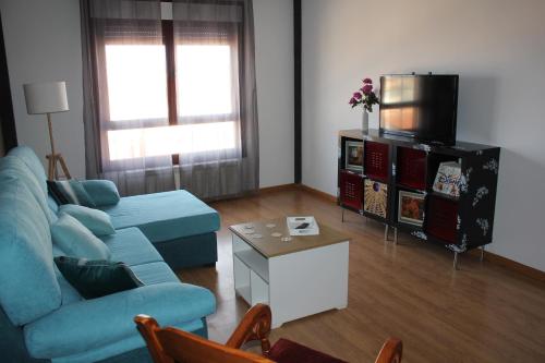 sala de estar con sofá azul y TV en Apartamento Ronda San Antón en Toro