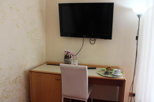 a desk with a chair and a television on a wall at Hotel Palace Masoanri's in Reggio di Calabria