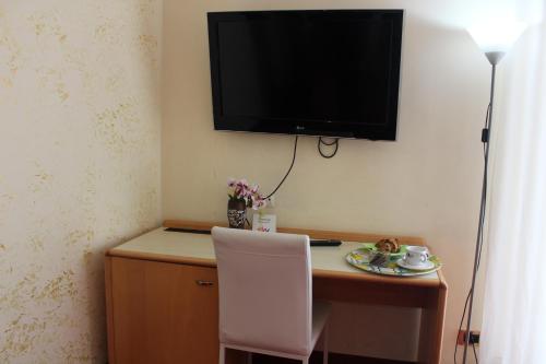 a desk with a chair and a television on a wall at Hotel Palace Masoanri's in Reggio Calabria