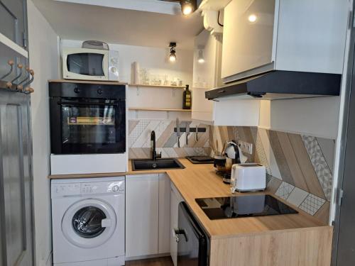 une cuisine avec un lave-linge et un micro-ondes dans l'établissement Studio coin nuit terrasse à 5 minutes de la plage N1, à Saint-Laurent-du-Var