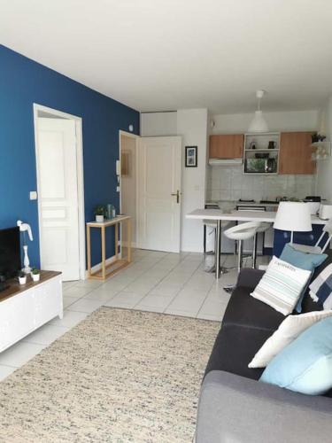 un salon avec un canapé et une cuisine dans l'établissement Appartement cosy proche rue piétonne et plages, à Capbreton