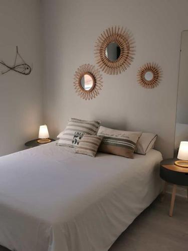 - une chambre avec un lit et deux miroirs sur le mur dans l'établissement Appartement cosy proche rue piétonne et plages, à Capbreton