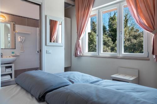 una camera con un letto e un lavandino e due finestre di Albergo Cristina a Lazise
