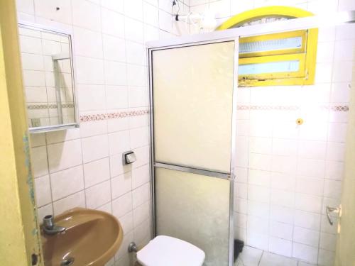 ein Bad mit einer Dusche, einem Waschbecken und einem WC in der Unterkunft Residencial Praia Bertioga - Pé na Areia in Bertioga