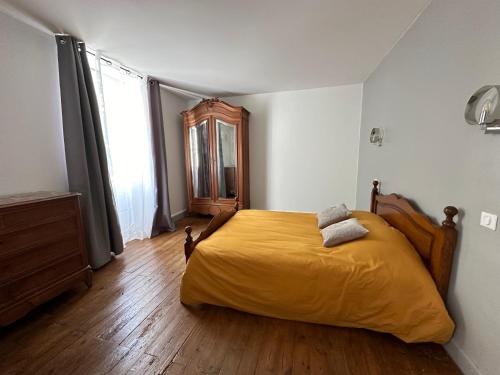 une chambre avec un grand lit jaune avec un plancher en bois dans l'établissement LA VIEILLE AUBERGE, à Saint-Geniez-ô-Merle