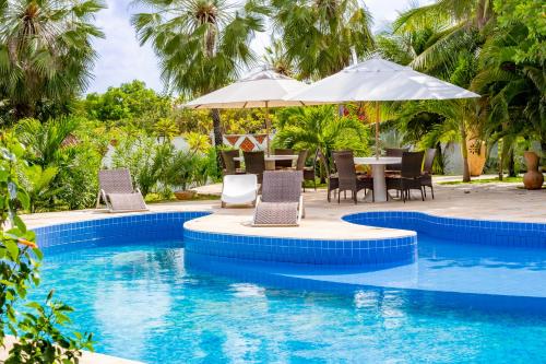 una piscina con sillas y una mesa con sombrilla en Refugios Parajuru - Casa Inge, en Parajuru