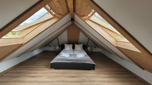 a attic bedroom with a bed and two windows at Bąbelkowa Chata Beskidy in Gilowice