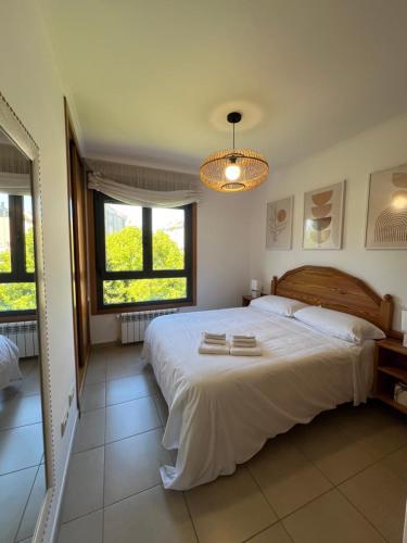ein Schlafzimmer mit einem großen weißen Bett mit Handtüchern darauf in der Unterkunft Trébol junto a playa Silgar in Sanxenxo