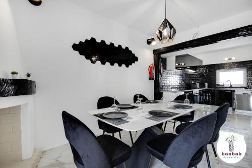 a dining room with a white table and black chairs at Villa Bellagio in Albufeira