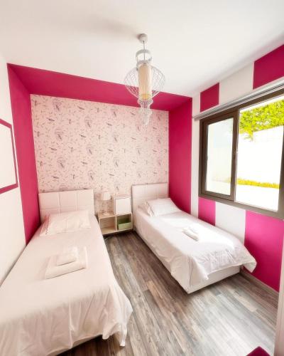 two beds in a room with pink walls at The Best Apartment on the beach 'Caesar Beach' Bogaz, North Cyprus in Boğaz