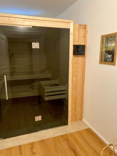 a glass shower door in a room with a wooden floor at Altes Forsthaus - Fewo "Hasenhorn", mit privater Sauna, Todtnau- Feldberg in Todtnau