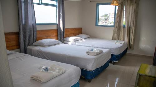 three beds in a room with three windows at Casa Blanca - San Pedro in San Pedro La Laguna