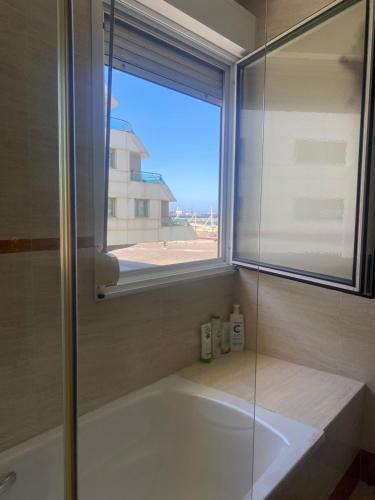 a bathroom with a bath tub and a window at Poniente Beach in Gijón