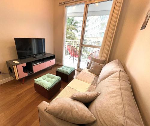 ein Wohnzimmer mit einem Sofa und einem Flachbild-TV in der Unterkunft Aconchego na Bela Cintra in São Paulo