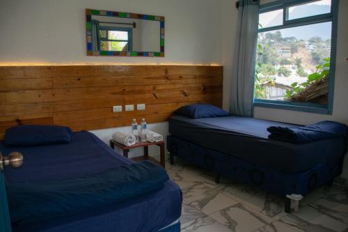 two beds in a room with a mirror and a window at Casa Blanca - San Pedro in San Pedro La Laguna
