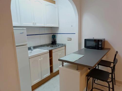 een keuken met witte kasten en een tafel met een magnetron bij Apartamento_Cala_Blanca in Alcossebre