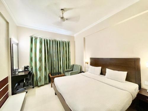 バラナシにあるHOTEL JANHVEE INN ! VARANASI - Forɘigner's Choice ! fully Air-Conditioned hotel with Parking availability, near Kashi Vishwanath Temple, and Ganga ghatのベッドと椅子付きのホテルルーム