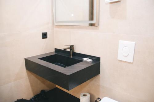 baño con lavabo negro y espejo en Hotel Rozafa, en Suharekë