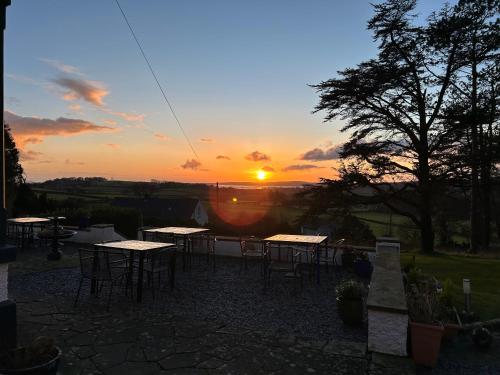 einen Sonnenuntergang mit Tischen und Stühlen auf einer Terrasse in der Unterkunft Uplands Inn Cartmel in Cartmel