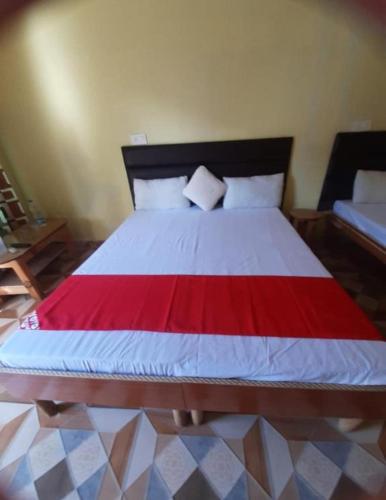 a bedroom with a large bed with a red and white blanket at Hotel surya tourist complex in Barkot