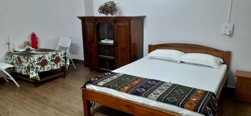 a bedroom with a bed and a dresser and a table at Tenam Garden homestay in Kalimpong