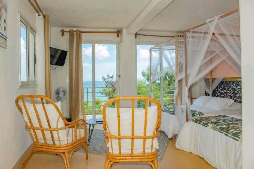 a bedroom with a bed and two chairs and a window at Hôtel RIZIKY in Diego Suarez